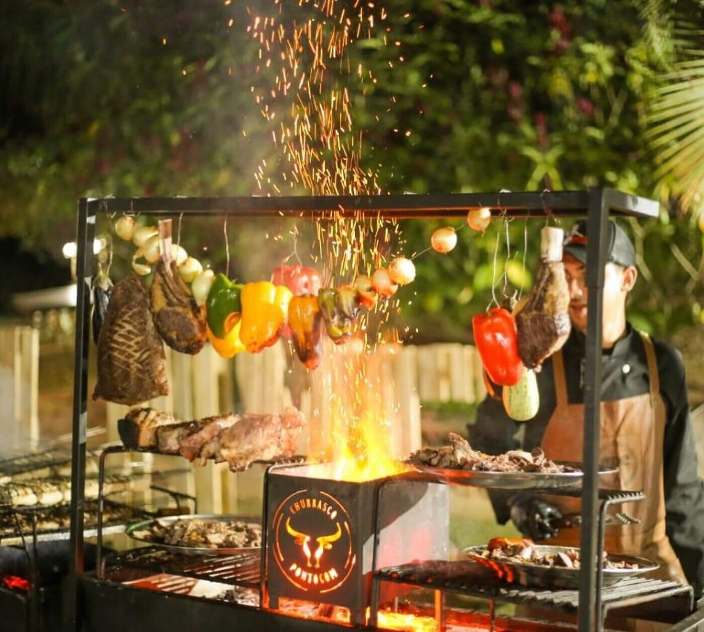 Fogo de chão com espetos de carne e legumes pendurados
