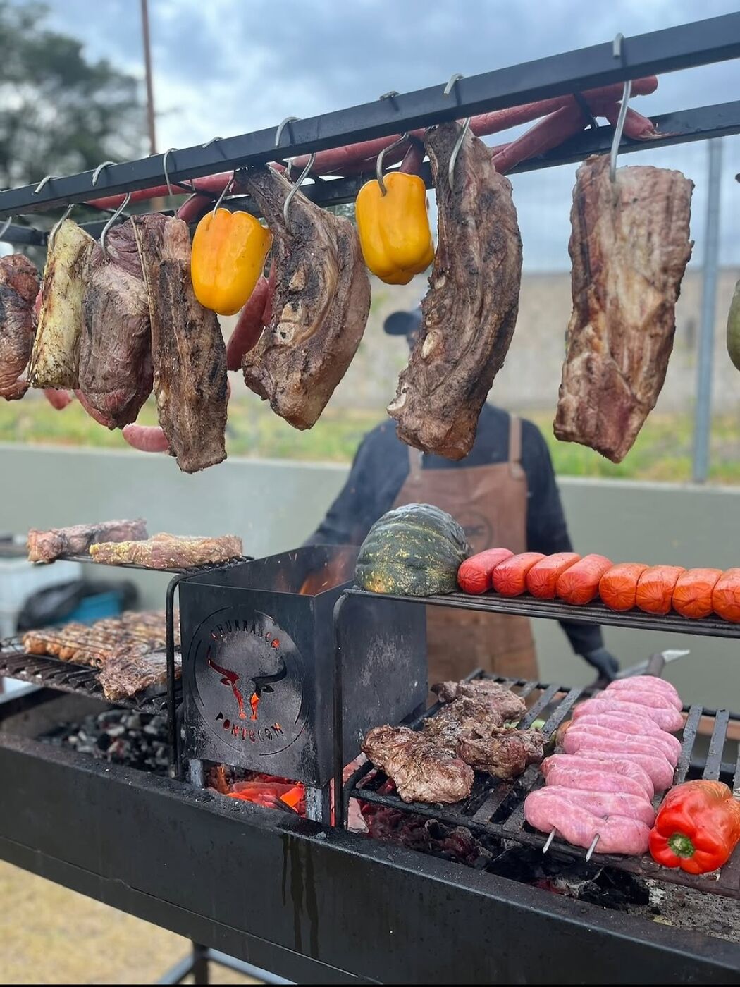 Parrilla montada em evento ao ar livre com costelas e legumes
