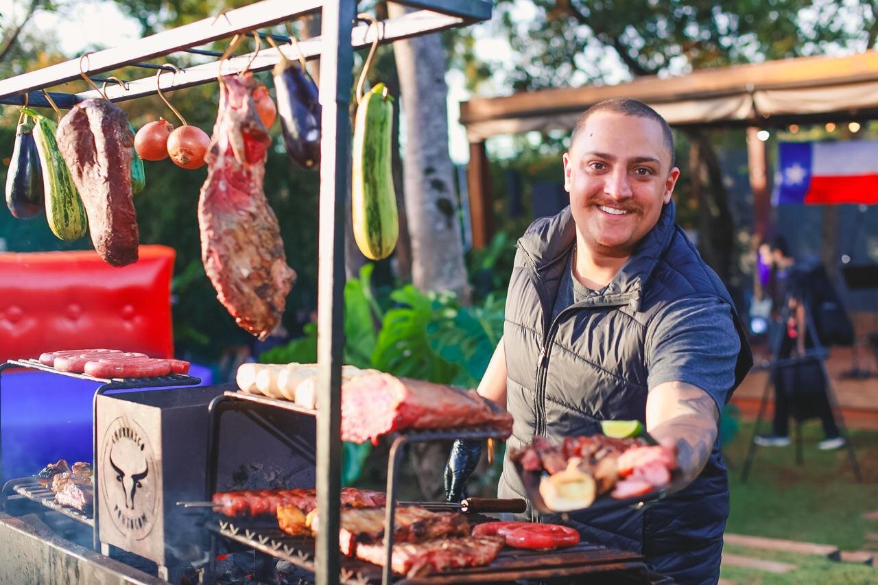 Churrasqueiro sorrindo enquanto serve um prato direto da grelha em festa ao ar livre
